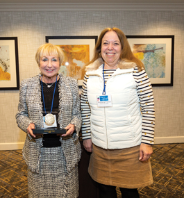 Two smiling women, one holding a plaque